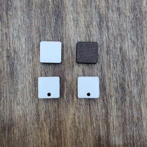 May include: Four square wooden tags, two white and two brown. The white tags have a small hole in the center. The brown tag is solid.