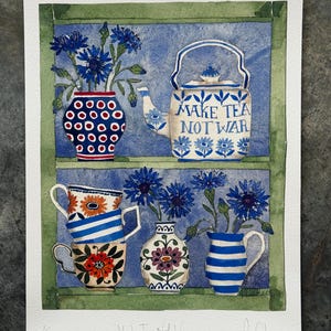 Pode incluir: Impressão em aquarela com uma chaleira azul e branca com o texto "MAKE TEA NOT WAR". A impressão também mostra vasos e xícaras de chá cheios de flores azuis, em um fundo azul dentro de uma moldura verde.