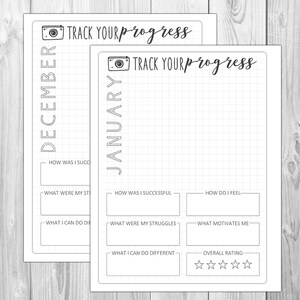 以下が含まれることがあります： カメラのアイコンと「TRACK YOUR progress」というテキストが書かれた白黒の印刷可能なプランナーページ。ページは12月と1月の2つのセクションに分かれており、各セクションには書き込み用のグリッドがあり、「どのように成功しましたか？」や「どのような課題がありましたか？」などのプロンプトが含まれています。