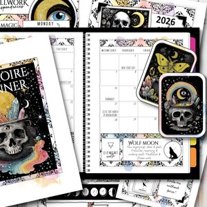 May include: A planner with a black spiral binding, featuring a calendar, stickers, and decorative elements. The stickers include a skull, a moth, and a rainbow. The planner has the text "2026" and "Wolf Moon".