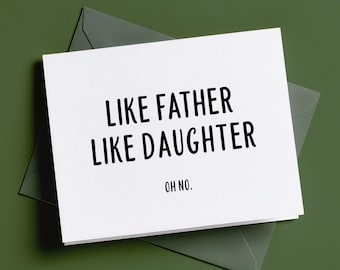 Puede incluir: Una tarjeta de felicitación rectangular blanca con texto negro sin remates que dice "LIKE FATHER LIKE DAUGHTER" seguido de "OH NO.". La tarjeta está colocada sobre un sobre de color verde oliva oscuro, creando un contraste claro entre el papel blanco y el fondo oscuro.