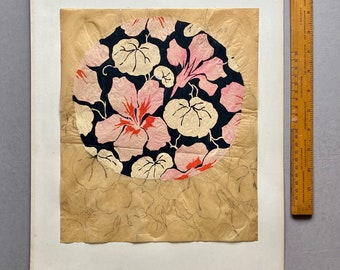 May include: A circular design featuring pink and white flowers with green leaves on a black background. The design is surrounded by a light brown paper with a faint outline of the same design.