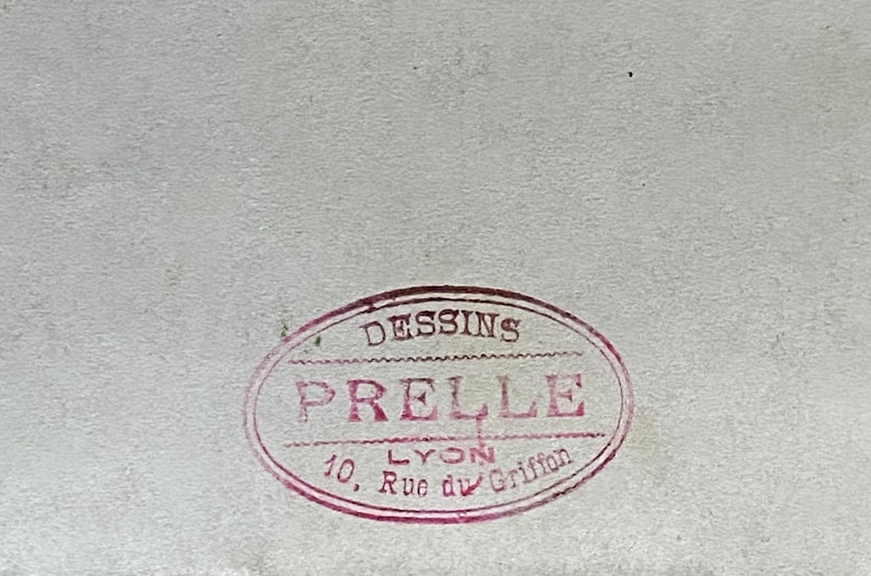 May include: A red oval stamp with the text "DESSINS PRELLE LYON 10, Rue du Griffon" in white.
