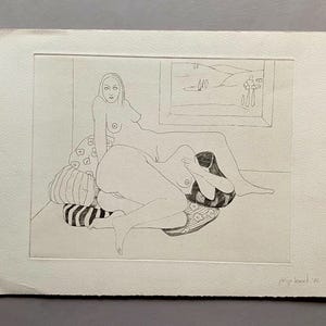Può includere: Un disegno in bianco e nero di due figure nude su un letto con cuscini a motivi. Le figure sono in posizione distesa, con la testa di una figura che riposa sulle gambe dell'altra. Il disegno è firmato "Philip Pearlstein 76" nell'angolo in basso a destra.