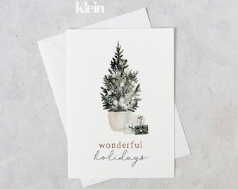 Può includere: Un biglietto bianco con un'illustrazione ad acquerello di un piccolo albero di Natale in vaso con ornamenti bianchi e regali. Il testo "wonderful holidays" è scritto in marrone sotto l'albero.