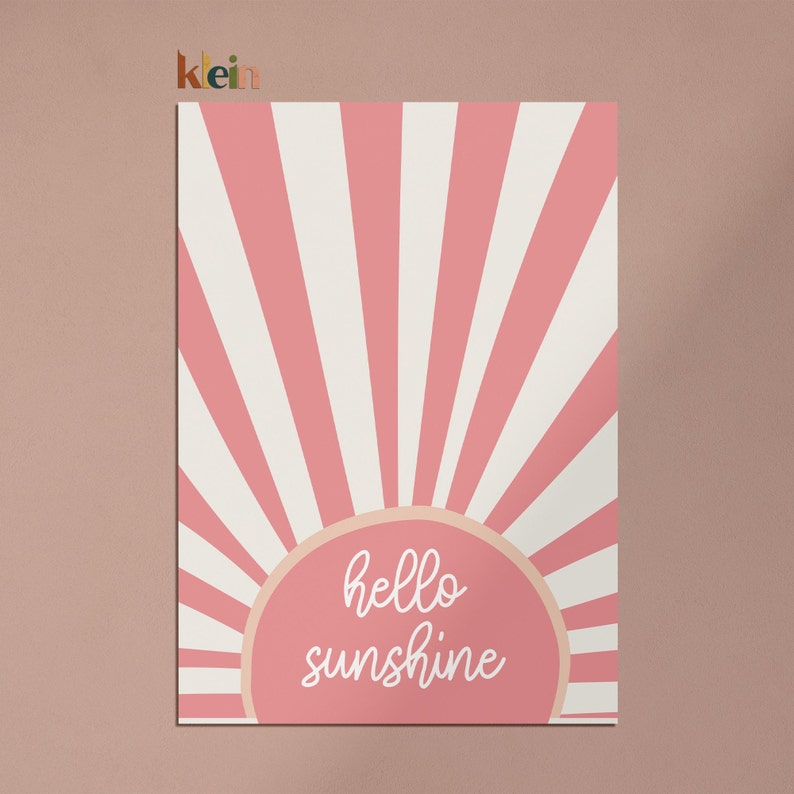 May include: Pink and white striped sunburst design with a peach-colored circle in the center. The circle has the text "hello sunshine" written in white.