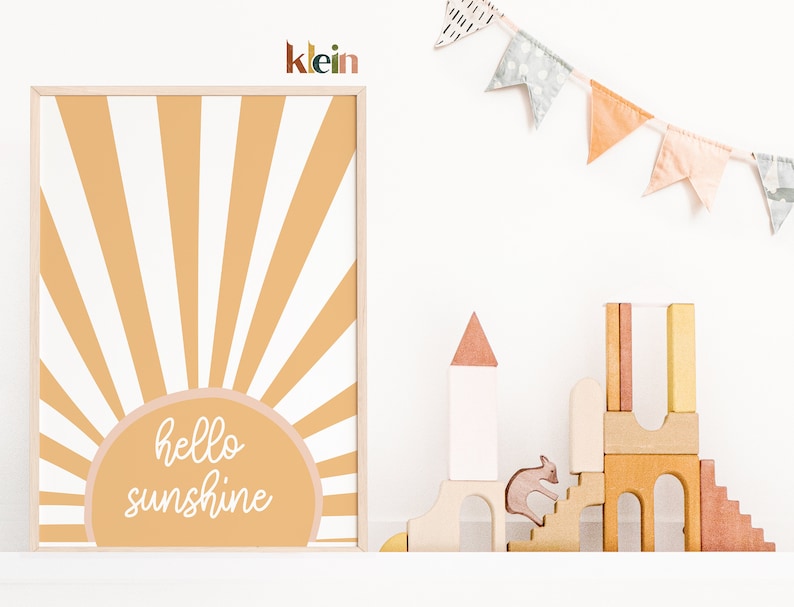 May include: A framed print with a yellow and white sunburst design and the text "hello sunshine" in white script. The print is hanging on a white wall with a wooden shelf below it. The shelf has a small wooden toy castle and a wooden animal figurine on it.