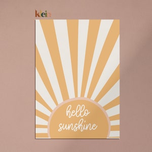 May include: A yellow and white striped sunburst design with a peach-colored circle in the center. The circle has the text "hello sunshine" written in white cursive.