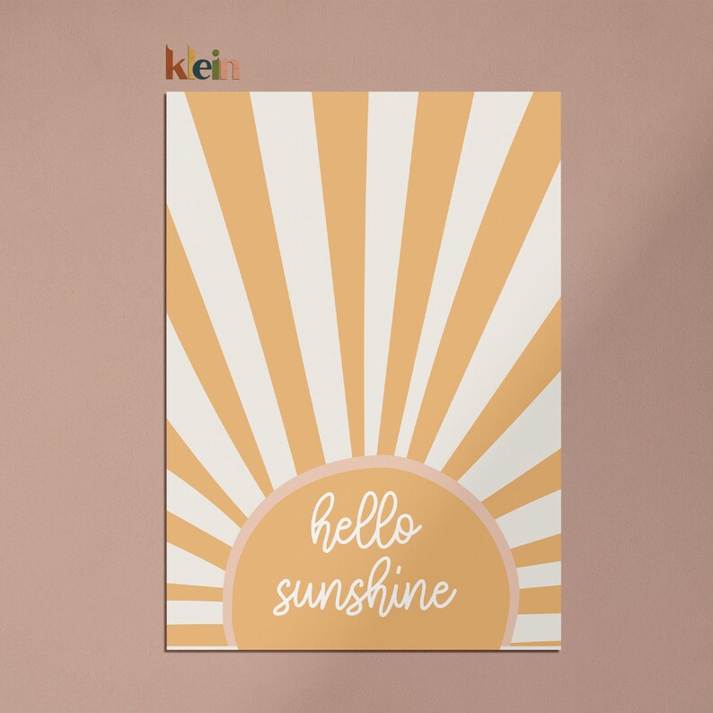 May include: A yellow and white striped sunburst design with a peach-colored circle in the center. The circle has the text "hello sunshine" written in white cursive.