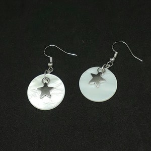 May include: A pair of white shell earrings with silver star charms. The earrings have a simple, elegant design.