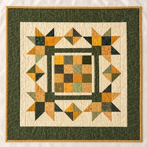 May include: A square quilt featuring a central grid of sixteen small fabric squares in shades of mustard yellow, olive green, and cream. The center is surrounded by a border of star-shaped patterns and a wide, dark green outer border with gold trim.