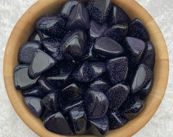 Puede incluir: Un bol lleno de piedras de arena azul pulidas. Las piedras son de un color azul intenso con un acabado brillante.