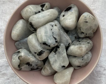 May include: A bowl of white and black moonstone tumbled stones. The stones are smooth and polished, with a variety of shapes and sizes.