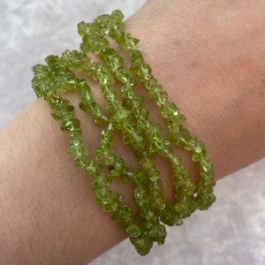 May include: A green peridot chip bead bracelet. The bracelet is made of multiple strands of small, irregular shaped beads.