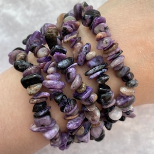 May include: A set of four purple and black gemstone bracelets. The bracelets are made of small, flat, irregular shaped stones.
