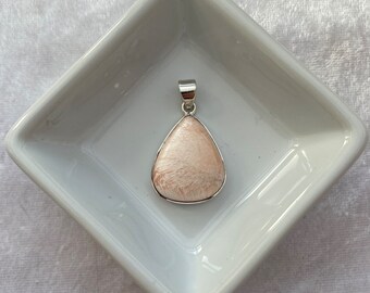 Può includere: Un ciondolo a forma di lacrima con una pietra rosa e bianca incastonata in argento.