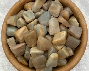May include: A bowl filled with tumbled sunstone crystals. The stones are a mix of light brown, beige, and white with a shimmery, iridescent quality.