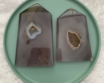 Op de afbeelding: Twee grijze agaat boekenleggers met een wit en bruin agaat patroon. De boekenleggers zijn piramidevormig.