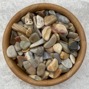 以下が含まれることがあります： 茶色、灰色、白の色合いの滑らかで磨かれた石が、ボウルいっぱいに詰められています。石はそれぞれユニークな模様と質感があり、視覚的に魅力的なディスプレイになっています。