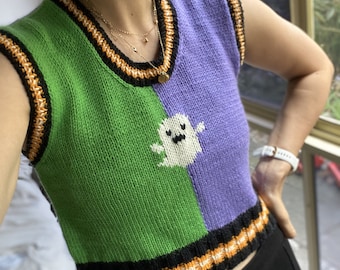 May include: A green and purple knitted vest with a ghost design and black, orange, and white trim.