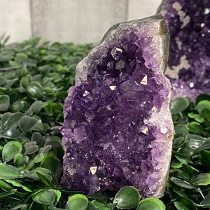 May include: A large amethyst crystal cluster with a deep purple color. The crystal is raw and has a natural, rough texture. It is a beautiful example of a natural gemstone.