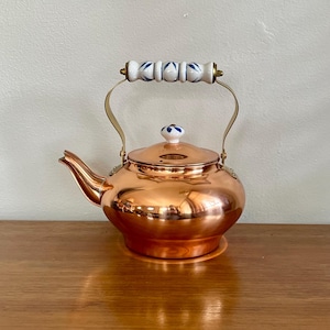 Könnte beinhalten: Eine weiße Keramik-Tasse mit schwarzem Henkel und dem Text "But First, Coffee" in schwarzer, fetter Schrift. Die Tasse steht auf einer weißen Oberfläche. Die Tasse ist etwa 10 cm hoch.