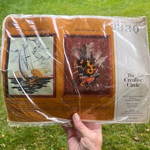 Puede incluir: Un kit de punto de cruz vintage de The Creative Circle. El paquete contiene dos diseños: "324 Sunset Sailing" con un velero y "0330 Wooden Decoy" con un pato y flores. El kit incluye tela estampada, hilo, agujas e instrucciones.
