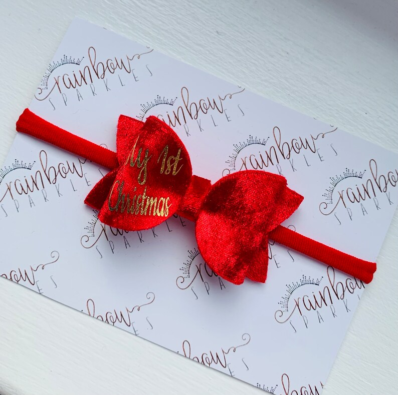 May include: Red velvet bow with a gold glitter "My 1st Christmas" inscription on a red headband.