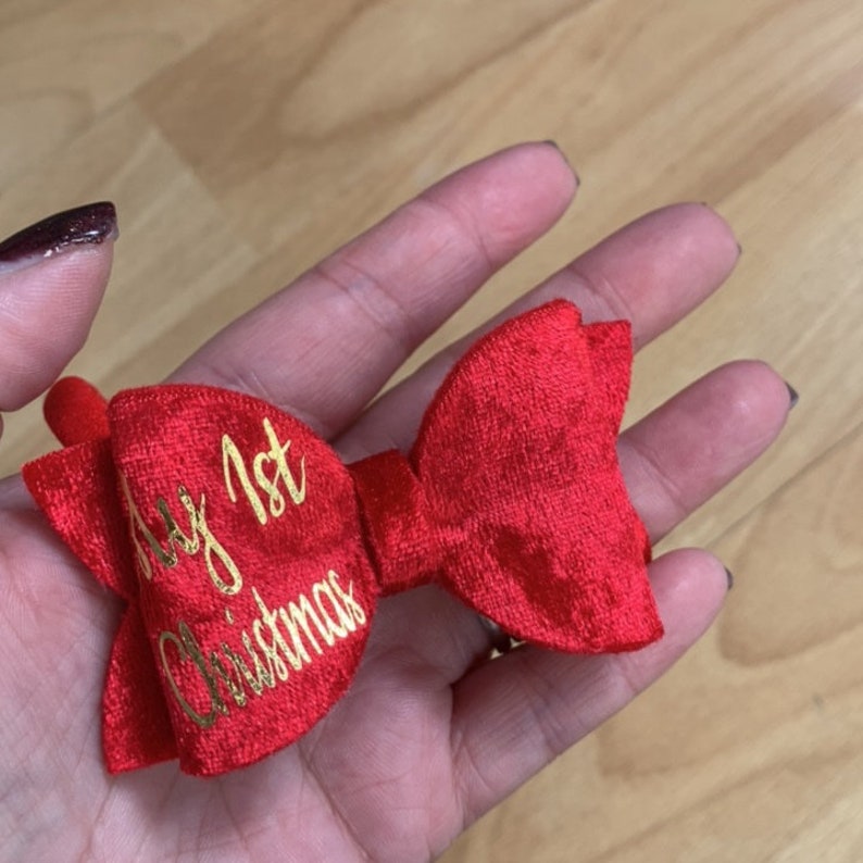 May include: Red velvet bow with a gold inscription that reads "My 1st Christmas".