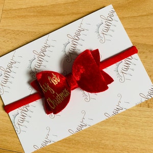 May include: Red velvet bow with a gold inscription that reads "It's a Christmas" on a white background with a repeating pattern of the words "rainbow sparkles".