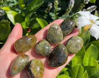 May include: A collection of seven green and black tumbled stones. The stones are smooth and polished, with a variety of shades of green and black.