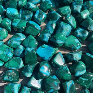 May include: A collection of polished malachite stones, showcasing a vibrant mix of deep green and turquoise hues. The stones have a smooth, rounded shape, with natural patterns and variations in color. These gemstones are ideal for jewelry making or decorative purposes.