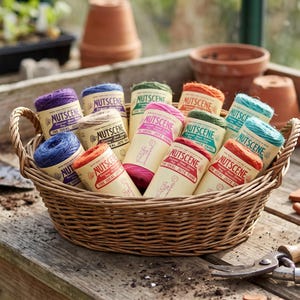 May include: A woven wicker basket filled with multiple spools of Nutscene jute twine in various colors including purple, blue, pink, green, orange, and teal. Each spool features a cream-colored paper label with the Nutscene brand name printed.