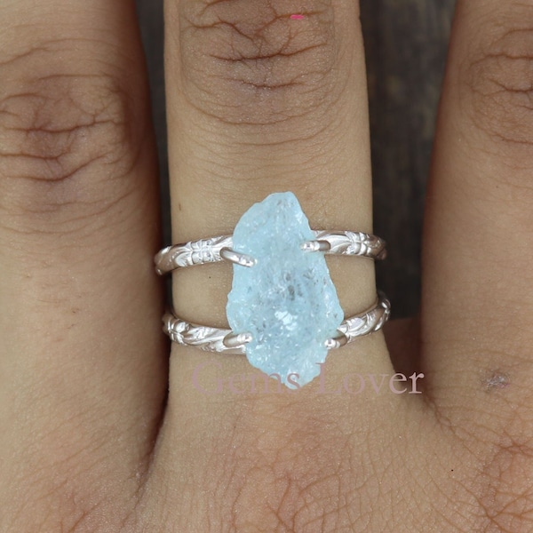 May include: A silver ring with a light blue aquamarine gemstone. The ring has a delicate, floral design on the band.