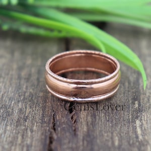 May include: A simple copper band ring with a textured edge. The ring is a classic design and would make a great gift for a special occasion.
