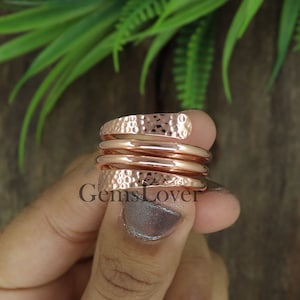 May include: A copper ring with a hammered finish. The ring is wrapped around itself three times, creating a unique and stylish design.