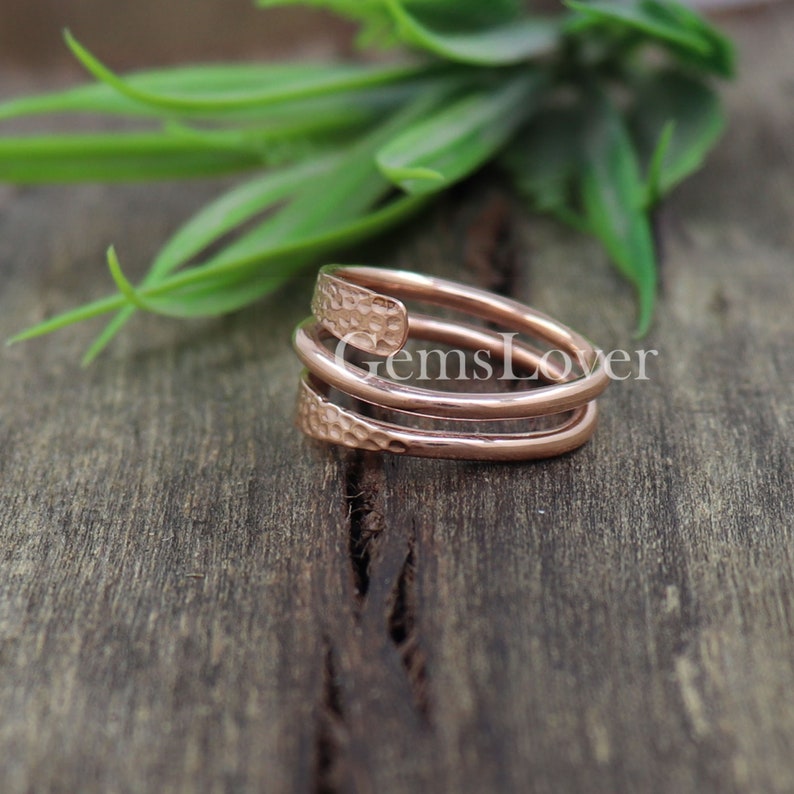 Pode incluir: Um anel de metal martelado em ouro rosa com um design em espiral.
