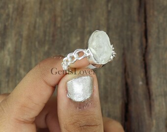 May include: A silver ring featuring a large, clear, raw quartz stone set in a chain link band.