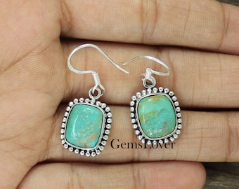 May include: A pair of silver dangle earrings with turquoise stones set in a square bezel. The stones have a green and brown marbled pattern.