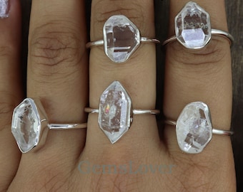 May include: Five silver rings with clear quartz gemstones. Each ring features a different shaped quartz crystal.