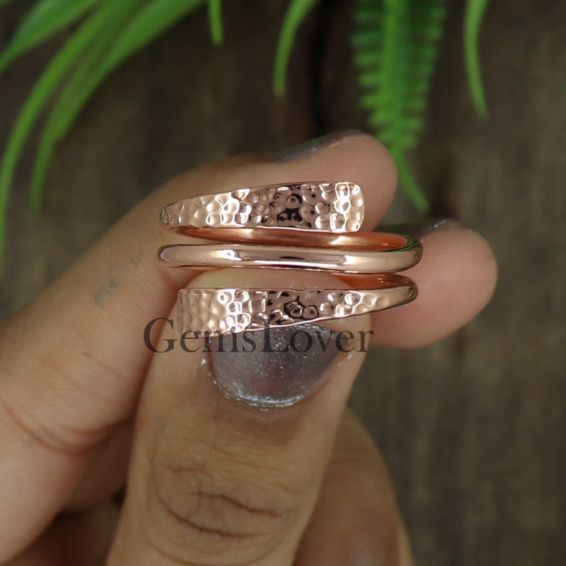 Pode incluir: Um anel de envolt&oacute;rio martelado em ouro rosa com uma banda lisa. O anel &eacute; feito de duas pe&ccedil;as que envolvem o dedo.