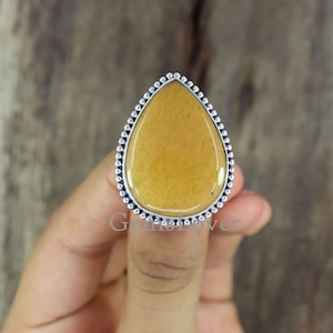 Peut inclure: Une bague en forme de larme avec une pierre précieuse jaune sertie dans une bélière en argent avec un bord perlé.