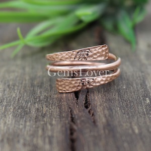 Pode incluir: Um anel de metal martelado em ouro rosa com um design torcido. O anel &eacute; feito de tr&ecirc;s bandas que se envolvem umas nas outras.