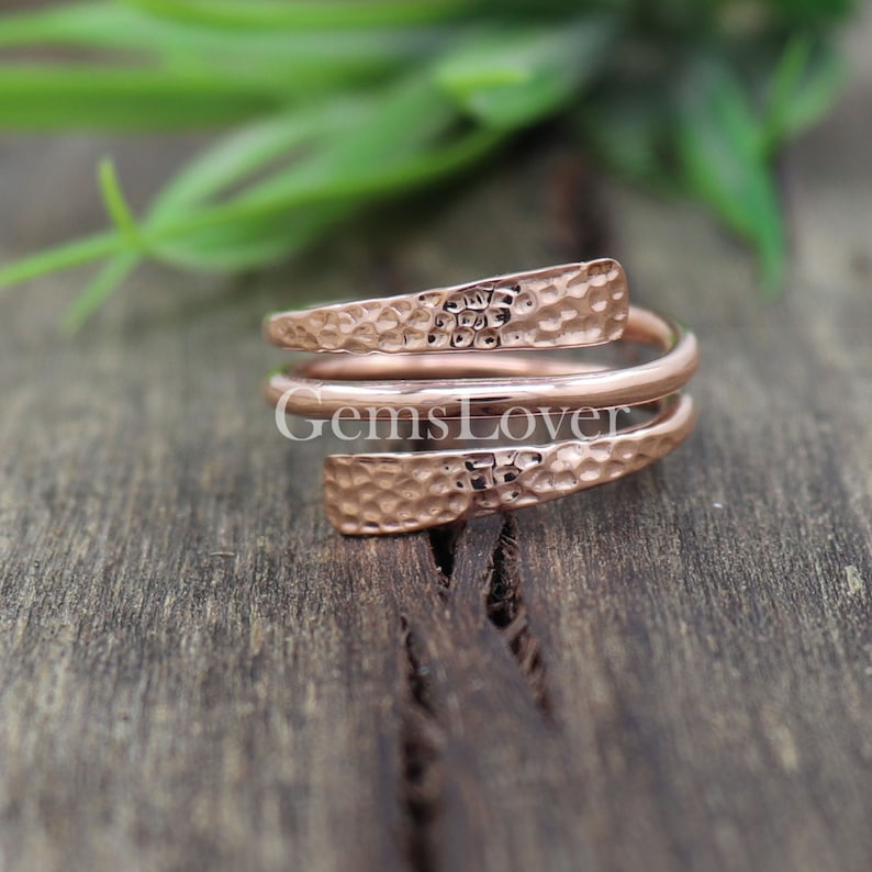 Pode incluir: Um anel de metal martelado em ouro rosa com um design torcido. O anel &eacute; feito de tr&ecirc;s bandas que se envolvem umas nas outras.
