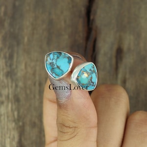 Puede incluir: Un par de pendientes de plata con piedras turquesa. Las piedras tienen forma triangular y presentan un patrón de mármol con motas doradas.