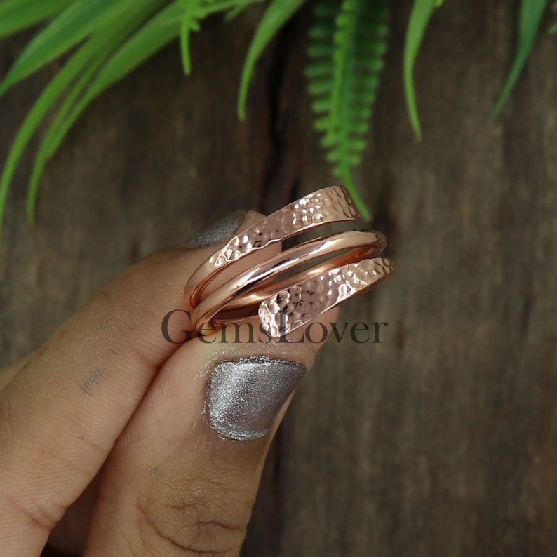 Pode incluir: Um anel de cobre martelado em ouro rosa com um design torcido. O anel &eacute; feito de duas bandas que est&atilde;o entrela&ccedil;adas.