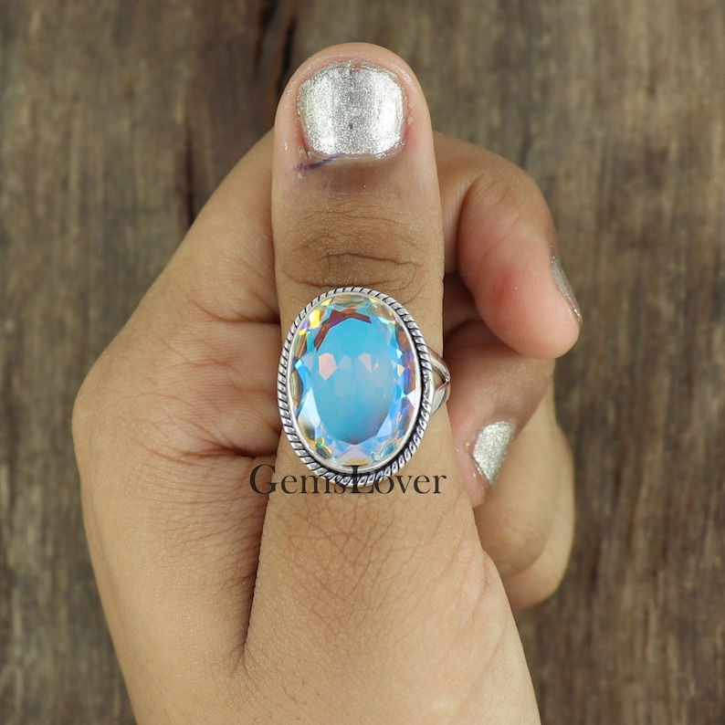 Peut inclure: Une bague en argent avec une grande pierre pr&eacute;cieuse bleue iris&eacute;e de forme ovale. La bague a une bande en argent torsad&eacute;e.