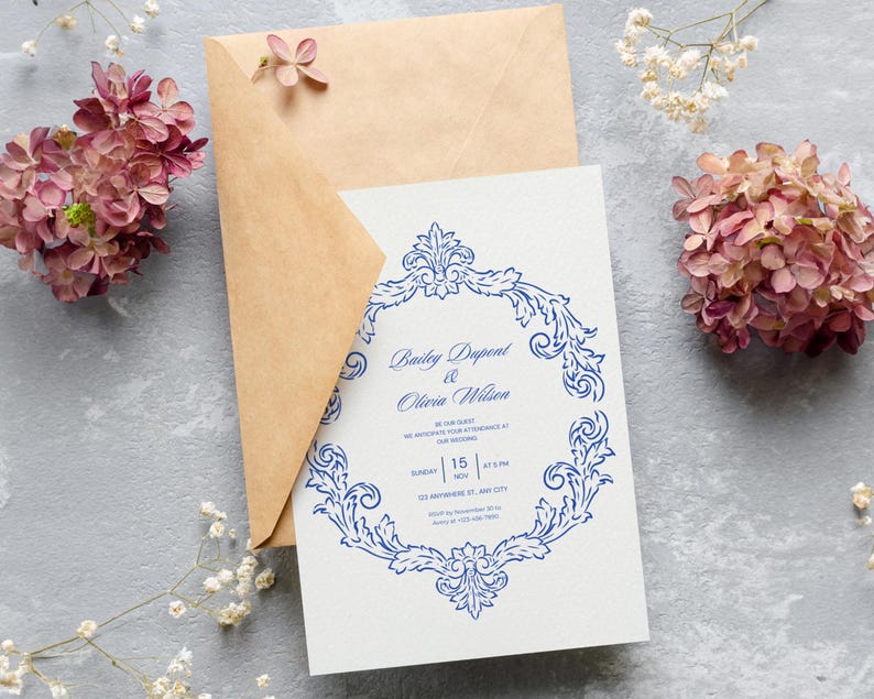 Puede incluir: Una invitaci&oacute;n de boda con un dise&ntilde;o floral azul y los nombres "Bailey Dupont & Olivia Wilson" impresos en una tarjeta blanca. La invitaci&oacute;n va acompa&ntilde;ada de un sobre marr&oacute;n y rodeada de flores rosas.