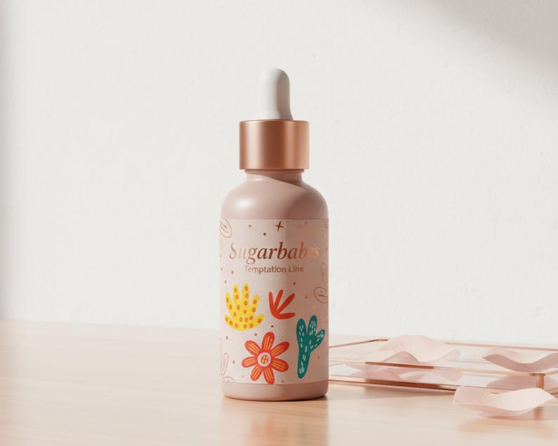 May include: A light pink bottle with a dropper top and a rose gold cap. The bottle has a label with the text "Sugarbabs Temptation Line" and colorful floral illustrations. The bottle is on a wooden surface.