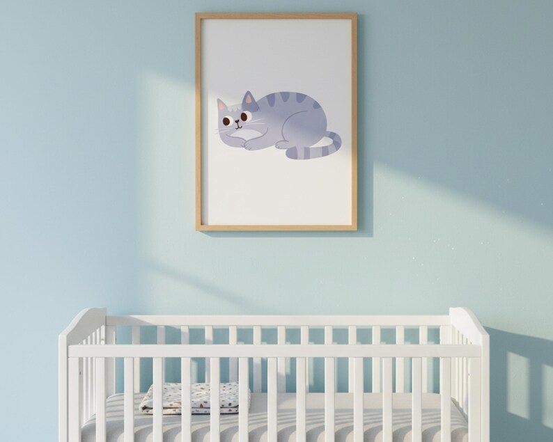Pode incluir: Uma impress&atilde;o emoldurada com uma ilustra&ccedil;&atilde;o de gato azul claro com listras azuis escuras. O gato est&aacute; deitado. A obra de arte &eacute; exibida acima de um ber&ccedil;o branco contra uma parede azul clara.